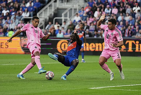 FC Cincinnati forward Kévin Denkey, center, falls to the pitch after a foul from Inter Miami CF defender Gonzalo Luján, right, during the first half of an MLS soccer game, in Cincinnati. 