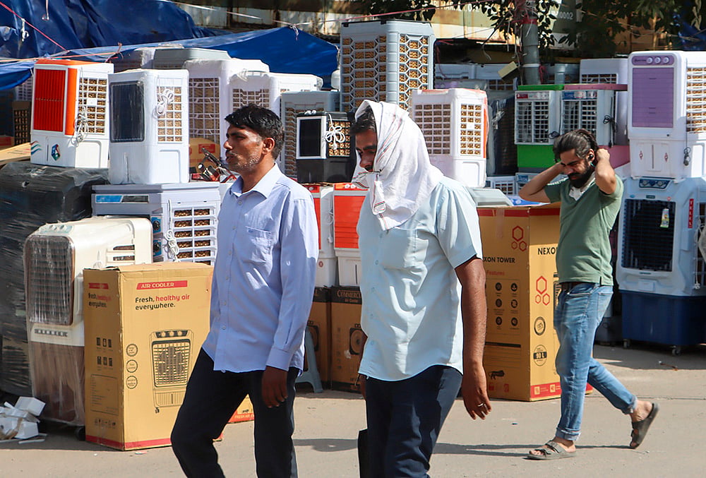 People walk past air coolers on sale amid scorching heat in Delhi