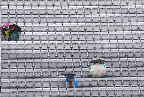 Spectators shelter with umbrellas as the quarter-final match between Karen Khachanov, of Russia, and Casper Ruud, of Norway, is suspended due to rain at the Italian Open tennis tournament in Rome.