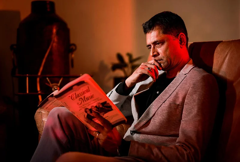 Man sitting in a chair reading a book titled Classical Music