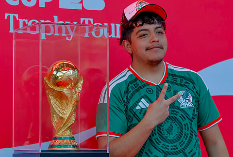 A soccer fan poses with the trophy during the FIFA World Cup Trophy Tour before the Atlanta Braves host the Chicago Cubs in a baseball game, in Atlanta. 