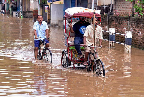 Guwahati: A rickshaw puller and a cyclist wade through a severely waterlogged road following a heavy rainfall, in Guwahati, Assam.