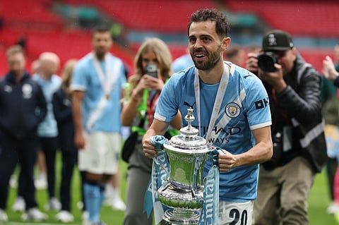 Manchester City's Bernardo Silva holds the winner's trophy after the English FA Cup final soccer match between Chelsea and Manchester City in London.