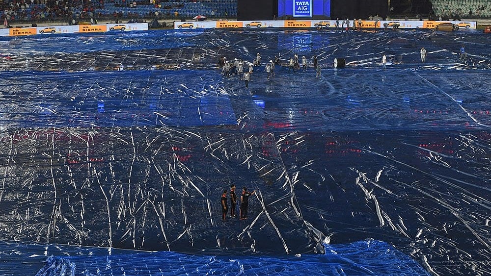 Umpires and groundsmen inspects the field after a spell of rain before the start of Indian Premier League cricket match between Royal Challengers Bengaluru and Kolkata Knight Riders in Raipur, India. - | Photo: AP/Abhijit Addya