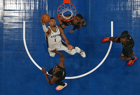 San Antonio Spurs forward Victor Wembanyama, middle, shoots over Minnesota Timberwolves guards Ayo Dosunmu (13), top, and Anthony Edwards (5), bottom, during the first half of Game 6 of a NBA basketball second-round playoff series in Minneapolis. 