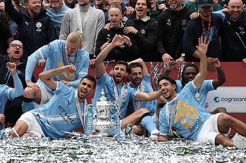 Manchester City players pose with the winner's trophy after the English FA Cup final soccer match between Chelsea and Manchester City in London.