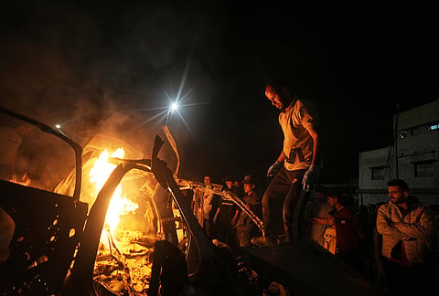 Palestinians gather around a vehicle struck by an Israeli strike in Gaza City.