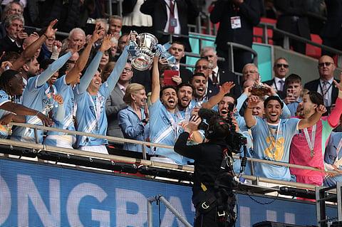 Manchester City players celebrate with the winner's trophy after the English FA Cup final soccer match between Chelsea and Manchester City in London.