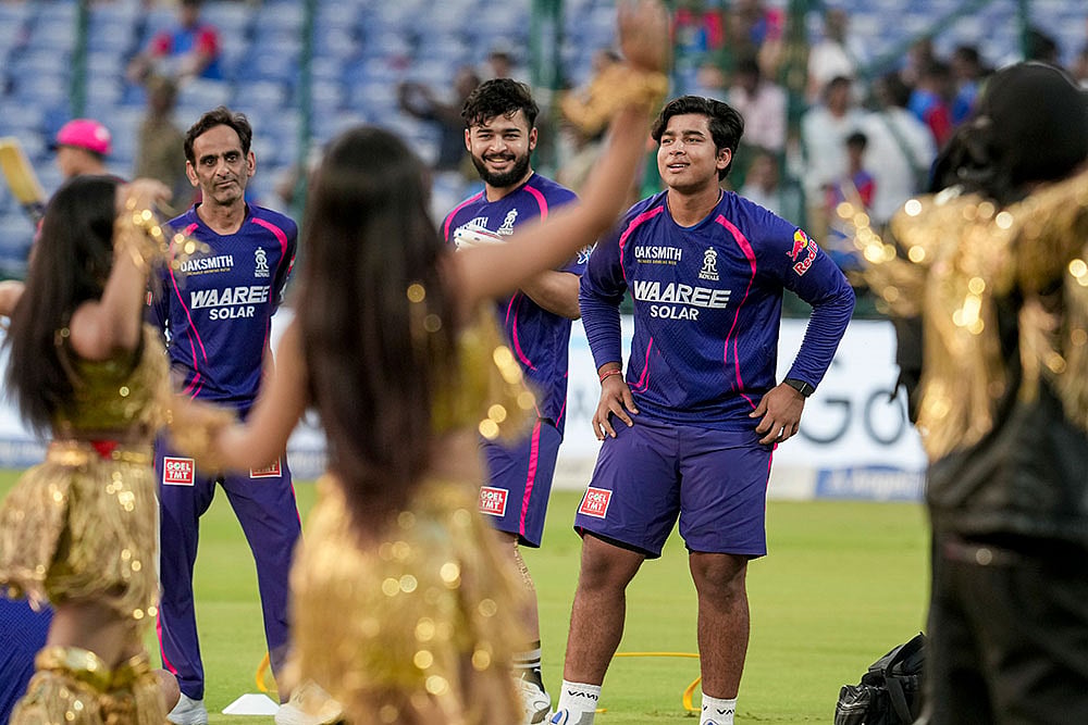 Rajasthan Royals Vaibhav Sooryavanshi, right, and captain Riyan Parag, centre, watch a performance of artist Himesh Reshammiya during an Indian Premier League (IPL) 2026 T20 cricket match between Delhi Capitals and Rajasthan Royals, in New Delhi.
