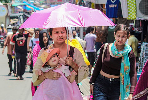 A woman covers herself and a child on a hot summer day, in Rishikesh, Uttar Pradesh.