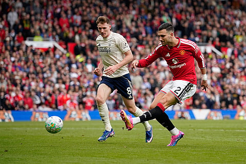 Manchester United's Diogo Dalot kicks the ball ahead of Nottingham Forest's Elliot Anderson during the English Premier League soccer match between Manchester United and Nottingham Forest in Manchester, England.