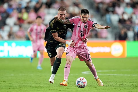 Portland Timbers defender Finn Surman, left, earns a yellow card as he defends against Inter Miami midfielder Lionel Messi (10) during the second half of an MLS soccer match in Miami.
