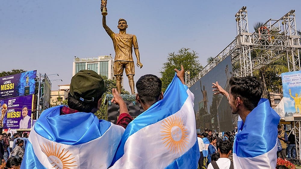 Fans cheer during the unveiling of Argentine footballer Lionel Messi's 70-feet statue, in Kolkata. Messi virtually unveiled the statue as part of his 'G.O.A.T. India Tour 2025'. - | Photo: PTI/Manvender Vashist Lav