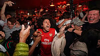 AP Photo/Alberto Pezzali : Arsenal supporters celebrate in a pub near the Arsenal stadium after Arsenal's soccer team won the Premier League title in London, Tuesday, May 19, 2026.
