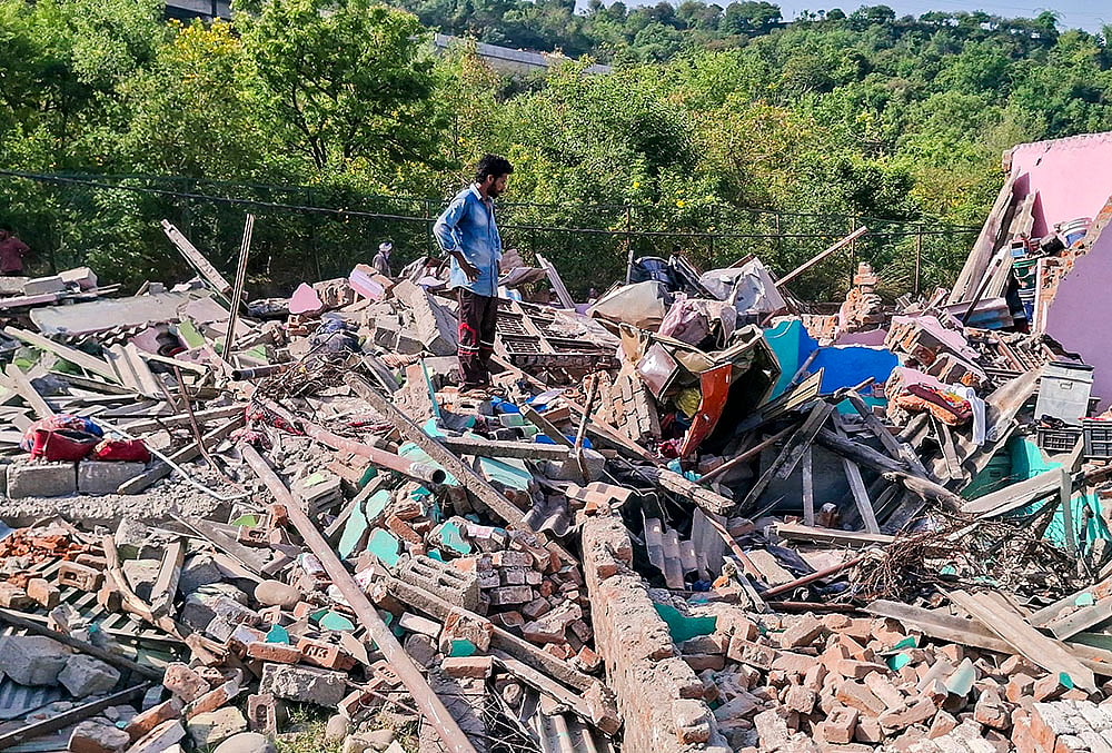 A man looks for his belongings following an anti-encroachment drive conducted by Forest Department and the police to clear alleged illegal settlements on the forest lands surrounding the lower side of Mahamaya Temple, in Jammu, Jammu and Kashmir. - | Photo: PTI