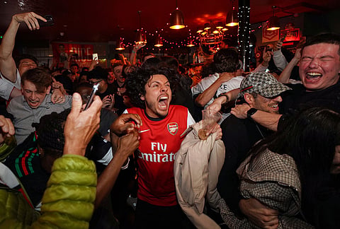 Arsenal supporters celebrate in a pub near the Arsenal stadium after Arsenal's soccer team won the Premier League title in London.
