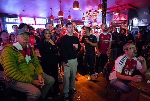 Arsenal supporters watch the Premier League match between Bournemouth and Manchester City on TV in a pub near the Arsenal stadium in London.