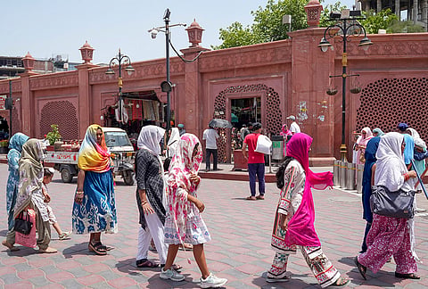 People cover themselves as they walk amid heat during the summer season, in Amritsar, Punjab.