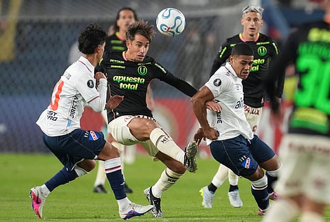 Martin Perez of Peru's Universitario, center, Alexander Dos Santos, left, and Juan De Los Santos of Uruguay's Nacional fight for the ball during a Copa Libertadores Group B soccer match in Montevideo, Uruguay.