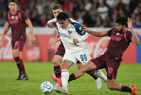 Cristian Tobar of Ecuador's Liga Deportiva Universitaria, center, and Damian Moreno of Argentina's Lanus, battle for the ball during a Copa Libertadores Group G soccer match in Quito, Ecuador.
