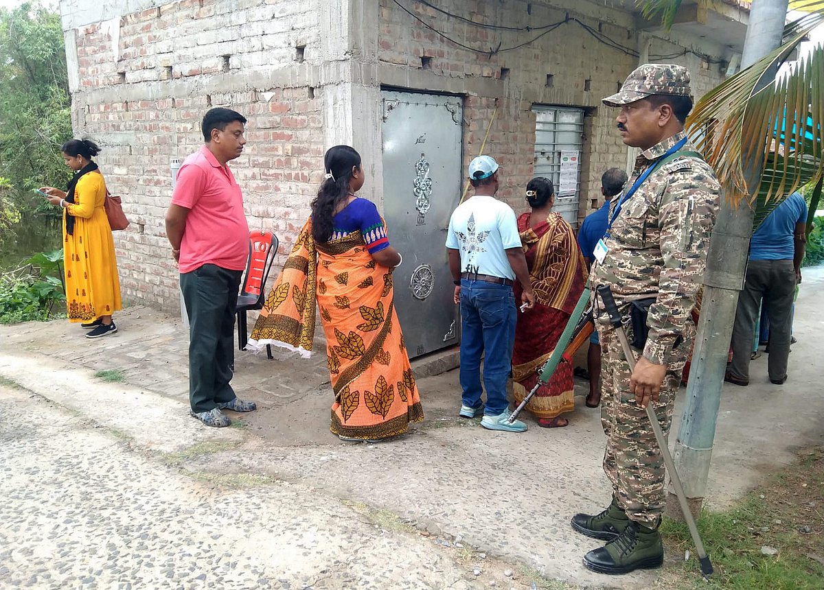 South 24 Parganas: A security official stands guard as people wait in a queue to cast votes during the re-election to the Falta assembly seat, in South 24 Parganas district, West Bengal, Thursday, May 21, 2026. - (PTI Photo)