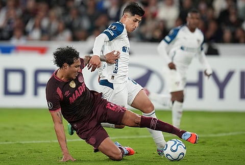 Jose Canale of Argentina's Lanus, left, tackles Fernando Cornejo of Ecuador's Liga Deportiva Universitaria during a Copa Libertadores Group G soccer match in Quito, Ecuador.