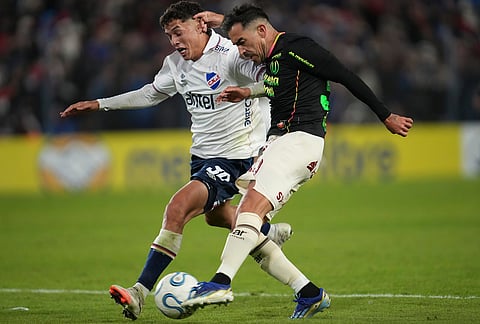 Lisandro Alzugaray of Peru's Universitario, right, kicks the ball challenged by Mateo Barcia of Uruguay's Nacional during a Copa Libertadores Group B soccer match in Montevideo, Uruguay.
