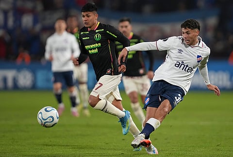 Mateo Barcia of Uruguay's Nacional, right, kicks the ball challenged by Jairo Concha of Peru's Universitario during a Copa Libertadores Group B soccer match in Montevideo, Uruguay.