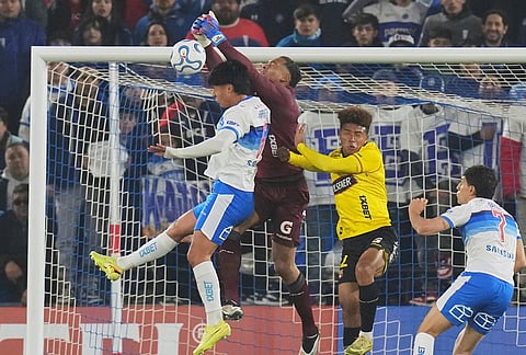 Goalkeeper Jose Contreras of Ecuador's Barcelona, center, blocks a shot as Sebastian Arancibia of Chile's Universidad Católica, left, attempts a header during a Copa Libertadores Group D soccer match in Santiago, Chile.
