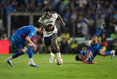 Pumas' Alvaro Angulo, center, dribbles the ball during the Mexican soccer league first leg final match against Cruz Azul in Mexico City.