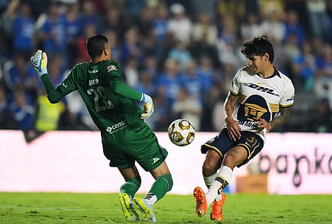 Cruz Azul's goalkeeper Kevin Mier, left, blocks a shot on goal by Pumas' Robert Morales during the Mexican soccer league first leg final match in Mexico City.