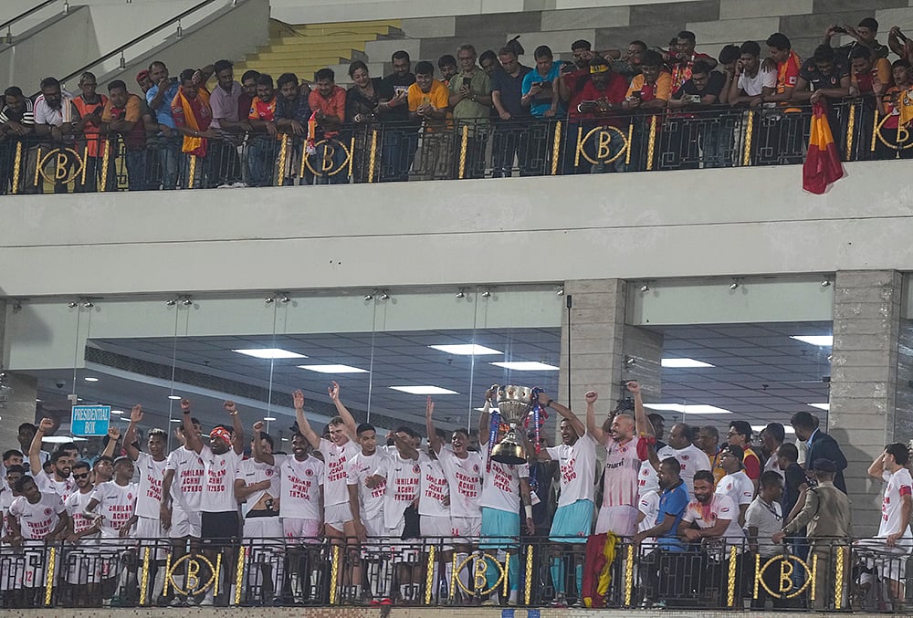 East Bengal players celebrate with the trophy after their team's victory in the Indian Super League (ISL) 2026 football match against Inter Kashi, in Kolkata. - | Photo: PTI/Swapan Mahapatra