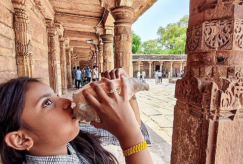 A young girl blows a conch as people offer prayers at the Bhojshala complex following the Madhya Pradesh High Court verdict declaring the site a Hindu temple dedicated to Goddess Vagdevi (Saraswati), in Dhar.