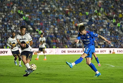 Pumas' Rodrigo Lopez, left, blocks a shot by Cruz Azul's Agustin Palavecino during the Mexican soccer league first leg final match in Mexico City.