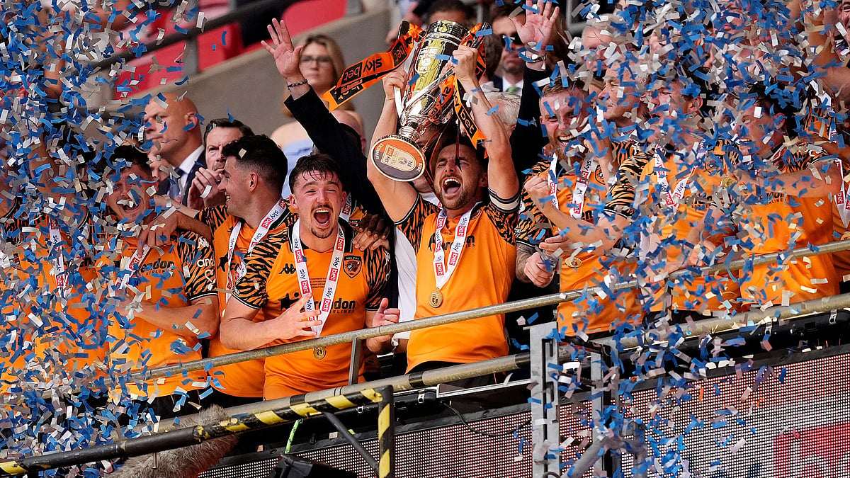 Hull City's Lewis Coyle lifts the trophy after winning promotion to the Premier League following the Championship play-off final between Hull City and Middlesbrough at Wembley Stadium, London, Saturday May 23, 2026 - (Jordan Pettitt/PA via AP)