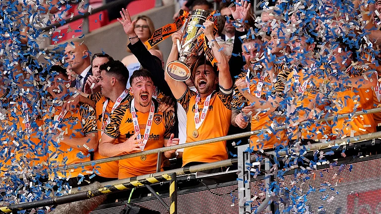 Hull City's Lewis Coyle lifts the trophy after winning promotion to the Premier League following the Championship play-off final between Hull City and Middlesbrough at Wembley Stadium, London, Saturday May 23, 2026 - (Jordan Pettitt/PA via AP)