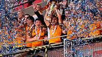 (Jordan Pettitt/PA via AP) : Hull City's Lewis Coyle lifts the trophy after winning promotion to the Premier League following the Championship play-off final between Hull City and Middlesbrough at Wembley Stadium, London, Saturday May 23, 2026