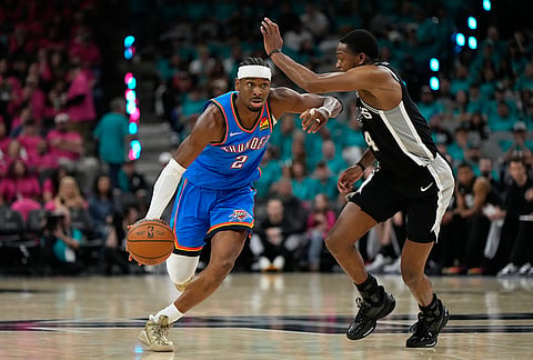 Oklahoma City Thunder guard Shai Gilgeous-Alexander (2) works toward the basket as San Antonio Spurs guard De'aaron Fox (4) defends during the second half of Game 3 in the Western Conference finals NBA basketball playoffs series in San Antonio.