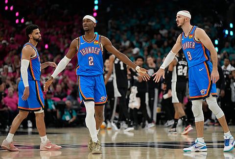 Oklahoma City Thunder guards Shai Gilgeous-Alexander (2) and Alex Caruso (9) high-five during the first half of Game 3 in the Western Conference finals NBA basketball playoffs series against the San Antonio Spurs in San Antonio.