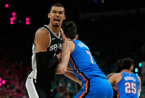 San Antonio Spurs forward Victor Wembanyama, left, reacts while defended by Oklahoma City Thunder center Chet Holmgren during the first half of Game 3 in the Western Conference finals NBA basketball playoffs series in San Antonio. 
