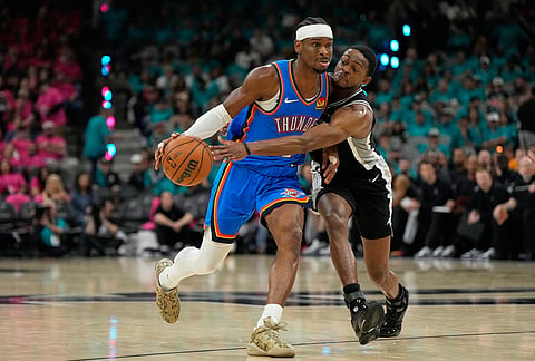 Oklahoma City Thunder guard Shai Gilgeous-Alexander, left, works toward the basket as San Antonio Spurs guard De'aaron Fox defends during the second half of Game 3 in the Western Conference finals NBA basketball playoffs series in San Antonio.