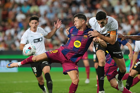 Barcelona's Robert Lewandowski, left, attempts a shot on goal challenged by Valencia's Cesar Tarrega during the Spanish La Liga soccer match between Valencia and FC Barcelona in Valencia, Spain.