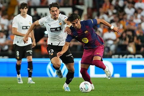 Valencia's Filip Ugrinic, left, challenges Barcelona's Ferran Torres during the Spanish La Liga soccer match between Valencia and FC Barcelona in Valencia, Spain.