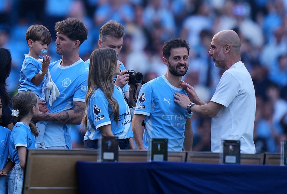 Manchester City's John Stones, left, Bernardo Silva and head coach Pep Guardiola stand during a farawell ceremony after their last game for the club after a Premier League soccer match between Manchester City and Aston Villa in Manchester, England. - | Photo: AP/Alastair Grant