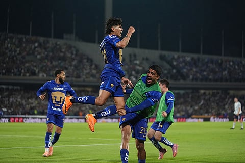 Pumas' Robert Morales, top, celebrates scoring his side's opening goal against Cruz Azul during the Mexican soccer league second leg final match in Mexico City.