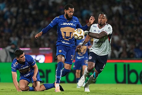 Pumas' Juninho, center, and Cruz Azul's Willer Ditta go for the ball during the Mexican soccer league second leg final match in Mexico City.