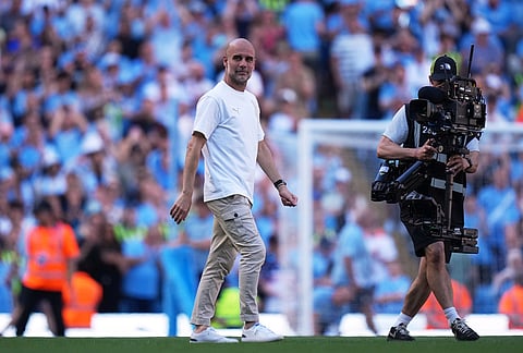 Manchester City's head coach Pep Guardiola walks on the pitch after a Premier League soccer match between Manchester City and Aston Villa in Manchester, England.