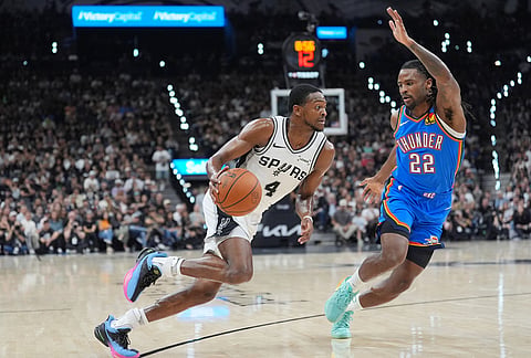 San Antonio Spurs guard De'aaron Fox (4) drives to the basket against Oklahoma City Thunder guard Cason Wallace (22) during the first half of Game 4 in the Western Conference finals NBA basketball playoffs series in San Antonio.