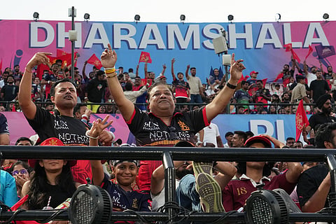 Royal Challengers Bengaluru supporters cheer for their team before the start of the Indian Premier League cricket match between Gujarat Titans and Royal Challengers Bengaluru in Dharamshala, India.