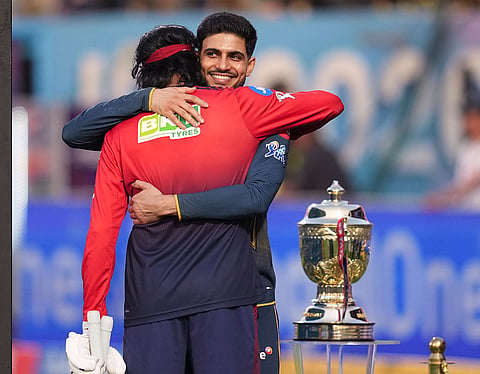 Gujarat Titans' captain Shubman Gill, back, with Royal Challengers Bengaluru's Krunal Pandya near the trophy before the Indian Premier League (IPL) 2026 T20 first qualifier cricket match between Royal Challengers Bengaluru and Gujarat Titans, in Dharamsala, Himachal Pradesh.